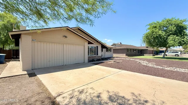 a backyard of a house with large trees and plants