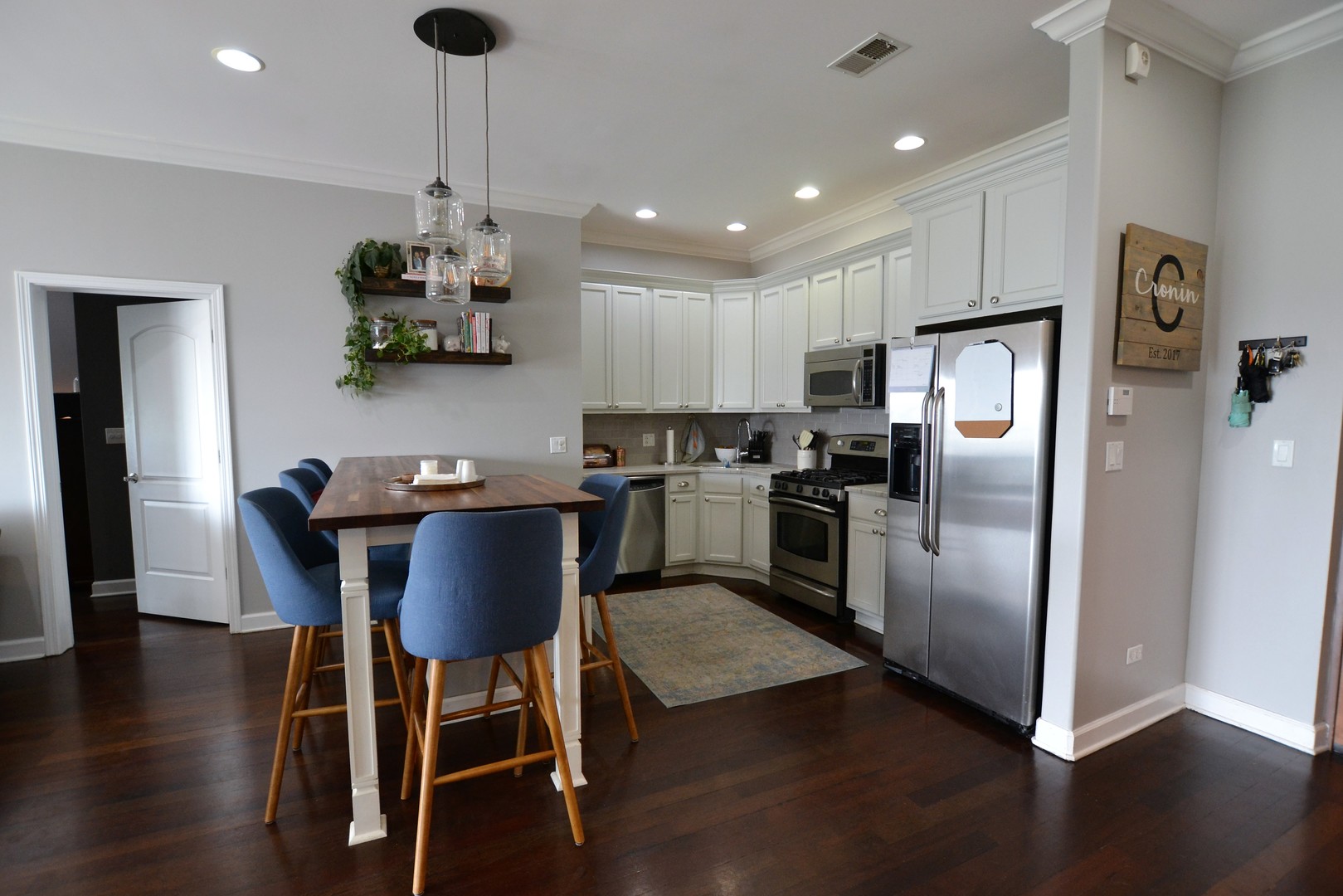 2900 West Irving Park Road, Unit 404 Chicago, IL 60618 - Photo 10 of 26 a kitchen with stainless steel appliances granite countertop a refrigerator a stove a microwave oven a sink with island and chairs with wooden floor