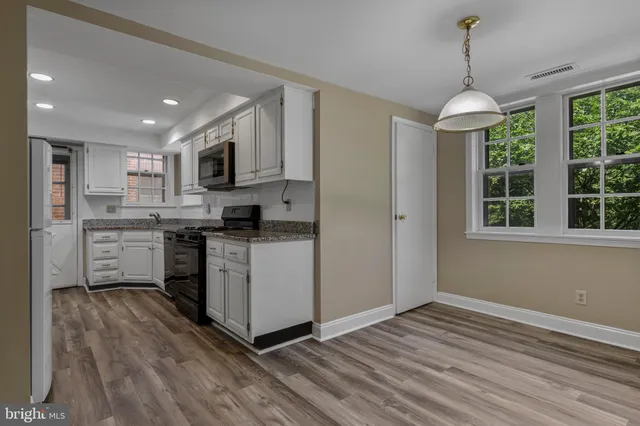 a kitchen with stainless steel appliances granite countertop a stove cabinets and wooden floor