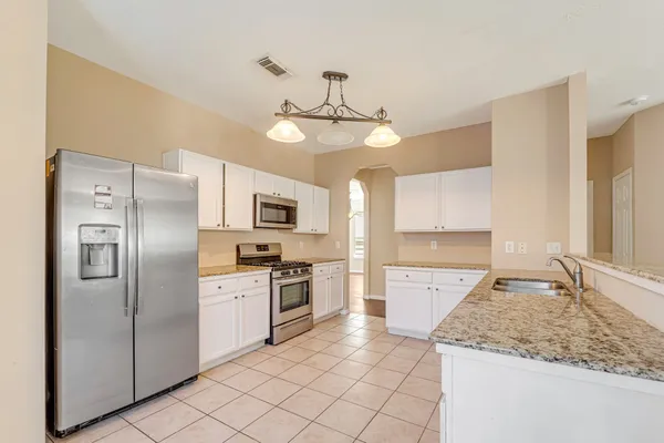 a kitchen with stainless steel appliances granite countertop a sink refrigerator stove and microwave