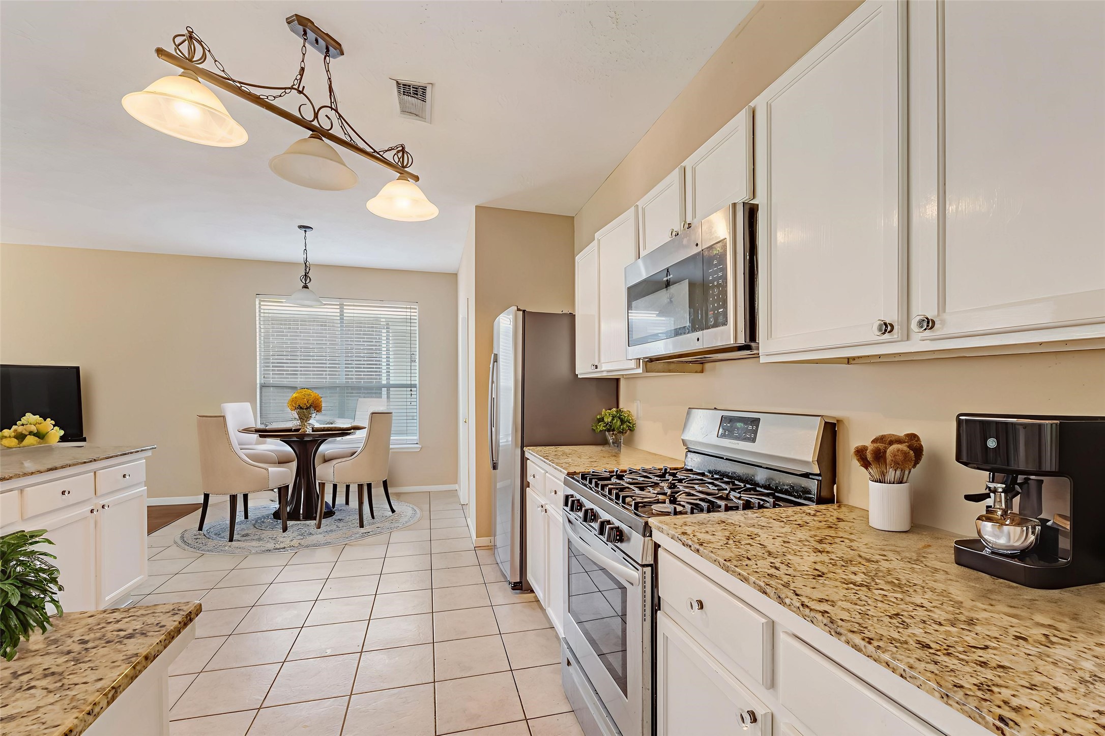 914 Chapwood Court Spring, TX 77373 - Photo 6 of 22 a kitchen with stainless steel appliances granite countertop a sink a stove a dining table and chairs with white cabinets