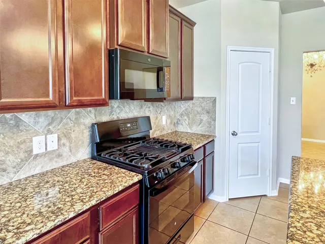 a view of an empty room with a fireplace and a chandelier fan