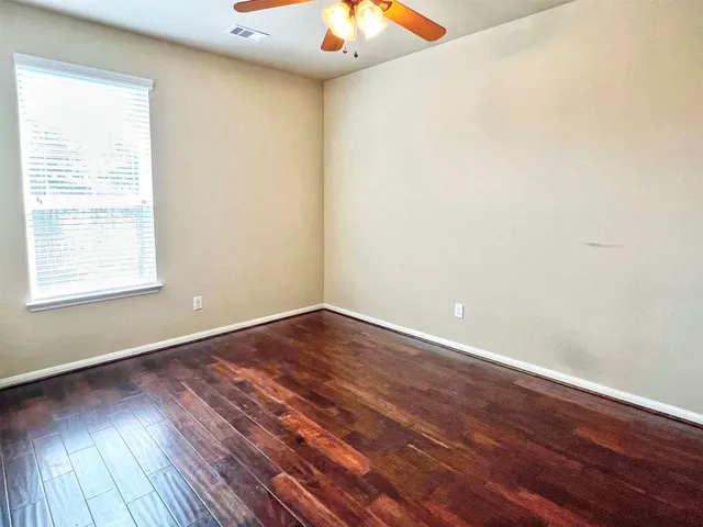 an empty room with a ceiling fan and wooden floor