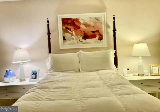 a bedroom with a bed and a lamp on dresser