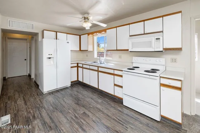a kitchen with granite countertop white cabinets and white appliances