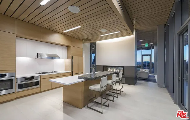 a room with stainless steel appliances kitchen island granite countertop lots of counter space and a sink