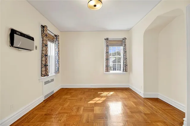 a view of an empty room with window and wooden floor