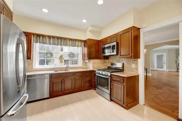 a kitchen with stainless steel appliances granite countertop a stove top oven a sink and a refrigerator