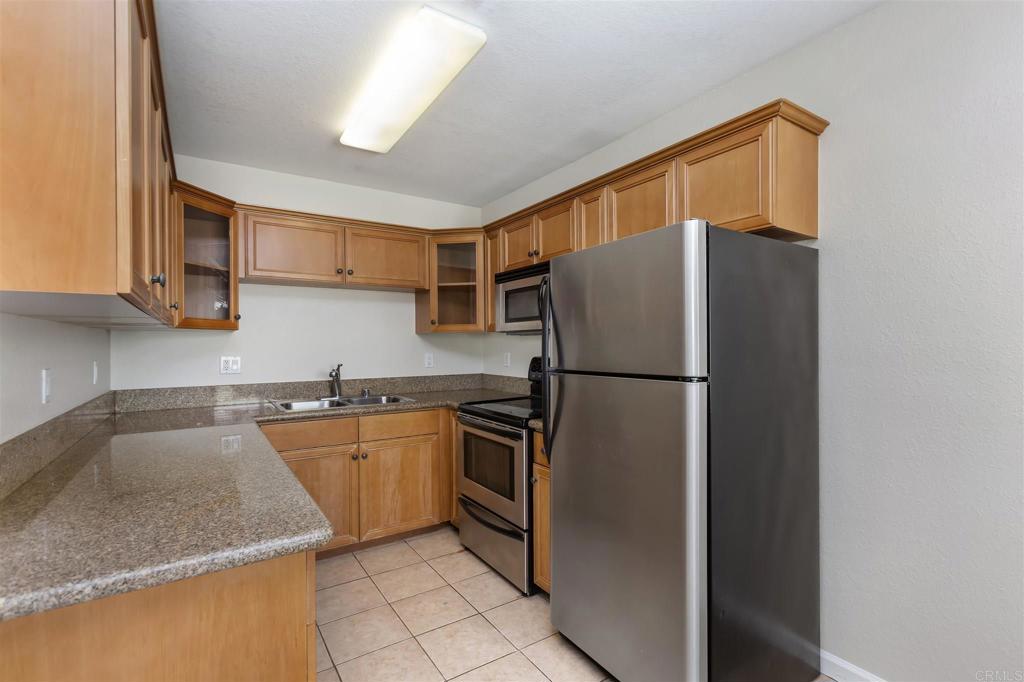 6602 Beadnell Way, Unit 26 San Diego, CA 92117 - Photo 14 of 25 a kitchen with stainless steel appliances granite countertop a refrigerator a sink and a stove