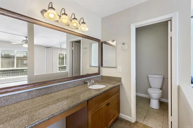 a bathroom with a granite countertop sink a toilet and a mirror