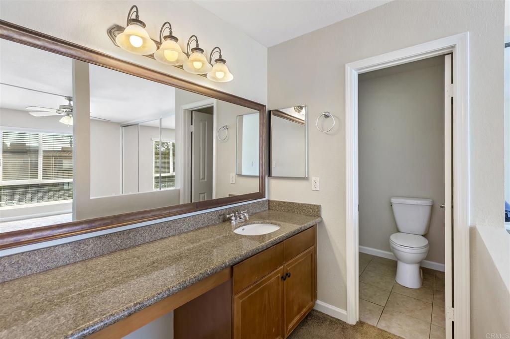 6602 Beadnell Way, Unit 26 San Diego, CA 92117 - Photo 23 of 25 a bathroom with a granite countertop sink a toilet and a mirror