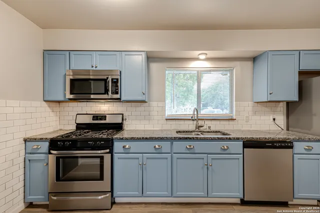 a kitchen with granite countertop a stove and a microwave