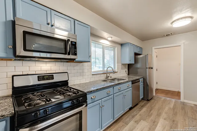 a kitchen with stainless steel appliances a stove microwave and sink