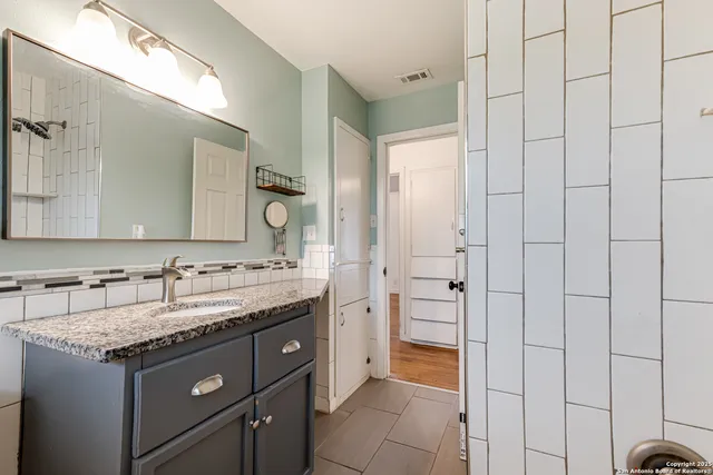a bathroom with a granite countertop sink and a mirror