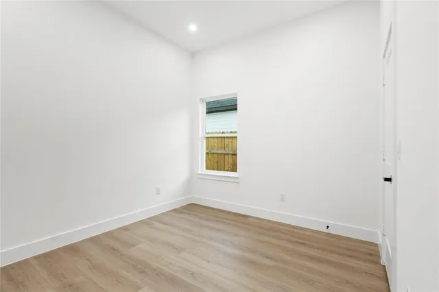 an empty room with wooden floor and window