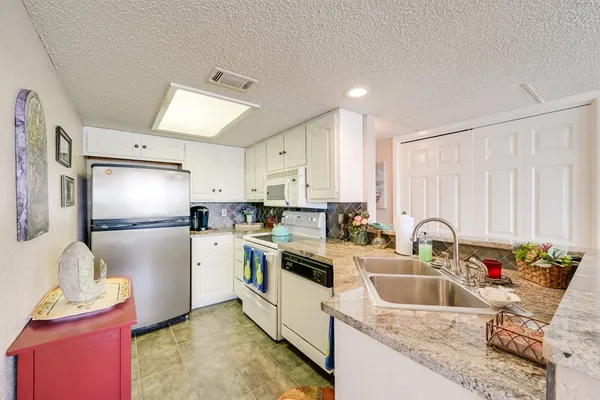 a kitchen with a refrigerator sink and white cabinets