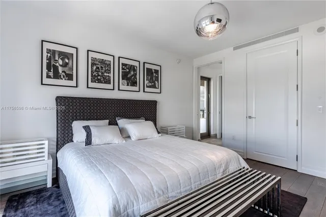 a bedroom with a bed and a flat tv screen on dresser