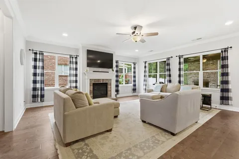 a living room with furniture a fireplace a flat screen tv and large window