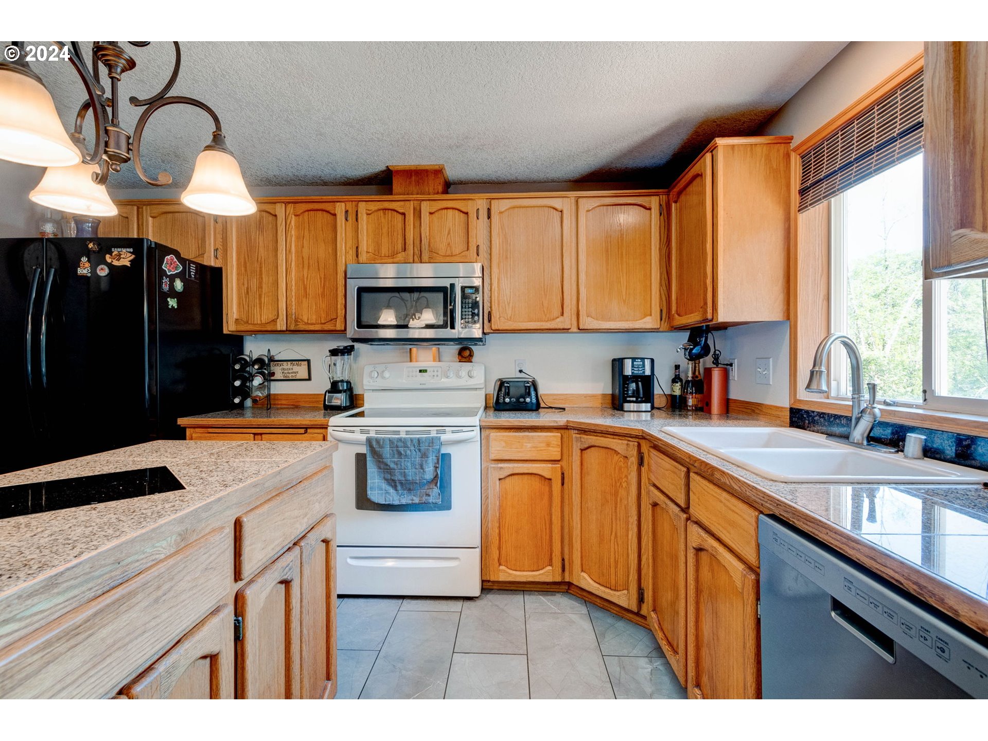30121 Northeast Harrison Road Battle Ground, WA 98604 - Photo 15 of 40 a kitchen with kitchen island granite countertop a sink cabinets stainless steel appliances and a large window