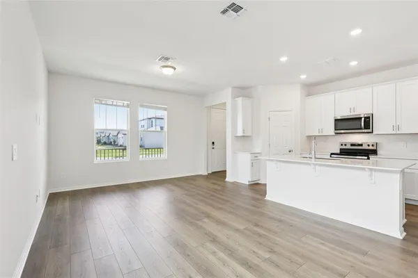a view of kitchen with stainless steel appliances refrigerator stove microwave and cabinets