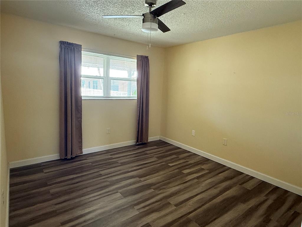 10038 62nd Avenue North, Unit 23 St. Petersburg, FL 33708 - Photo 8 of 25 an empty room with wooden floor fan and windows