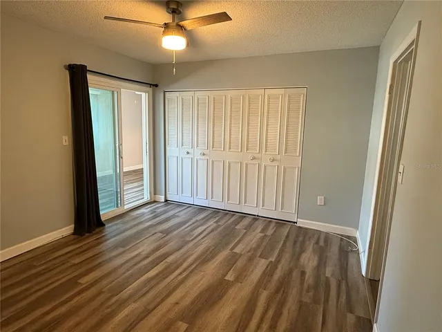 an empty room with wooden floor fan and windows