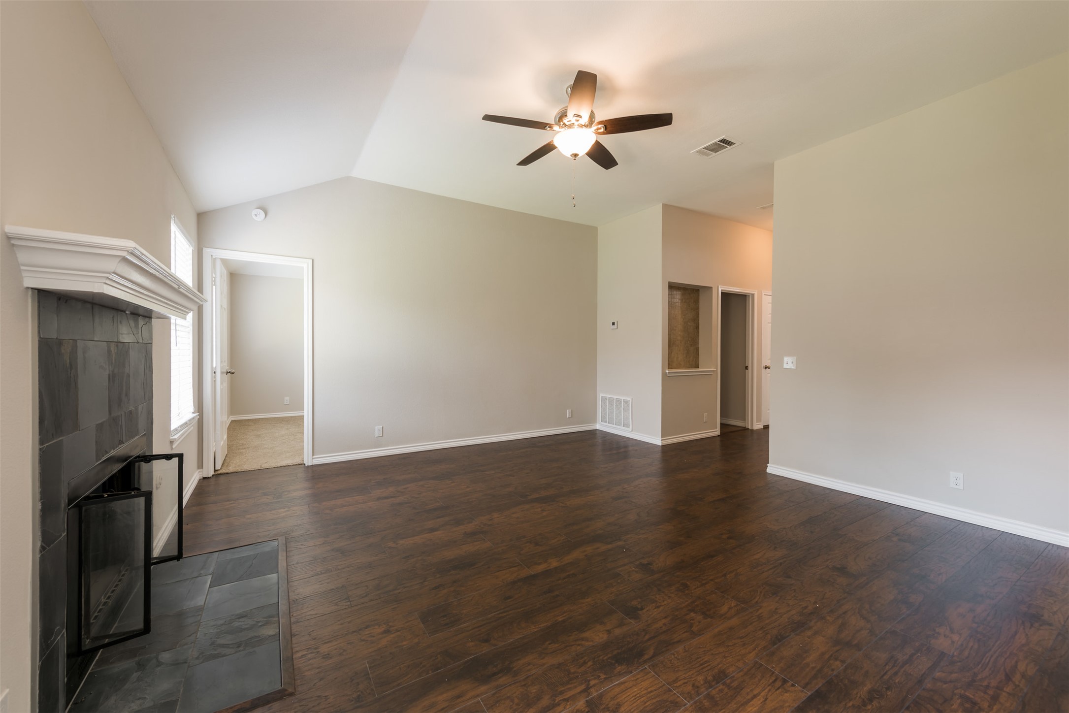 5703 Teri Road Austin, TX 78744 - Photo 4 of 16 a view of an empty room with wooden floor and a ceiling fan