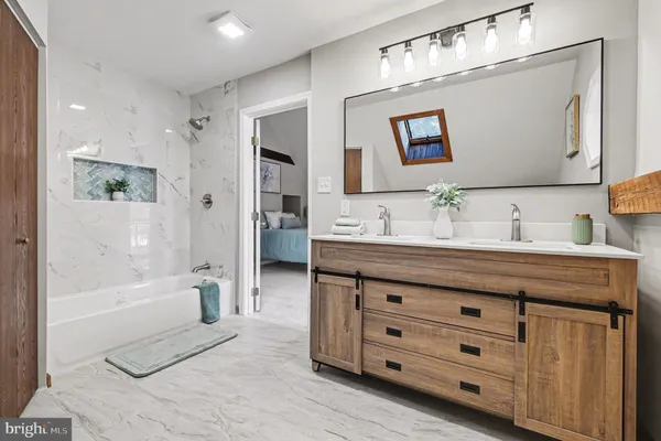 a spacious bathroom with a granite countertop sink a mirror a bathtub and shower