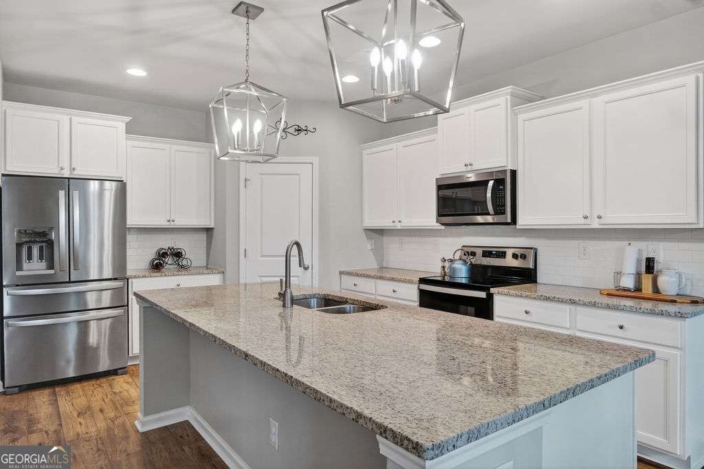 280 Greystone Court Winder, GA 30680 - Photo 13 of 40 a kitchen with kitchen island granite countertop stainless steel appliances a sink stove and refrigerator