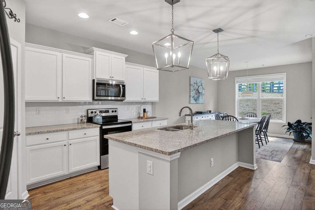 280 Greystone Court Winder, GA 30680 - Photo 15 of 40 a kitchen with stainless steel appliances granite countertop a sink a stove and a wooden floors