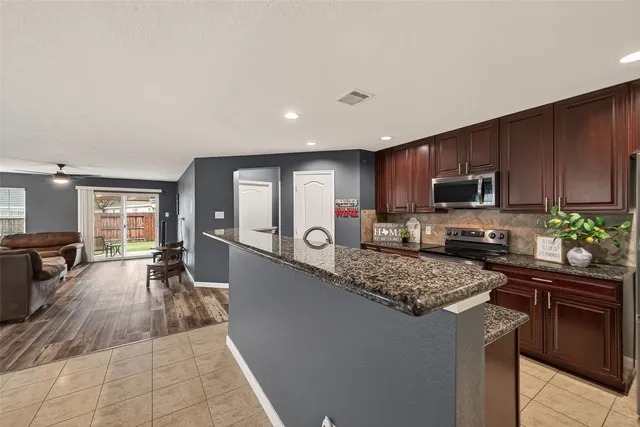 a kitchen with granite countertop a sink counter top space appliances and cabinets