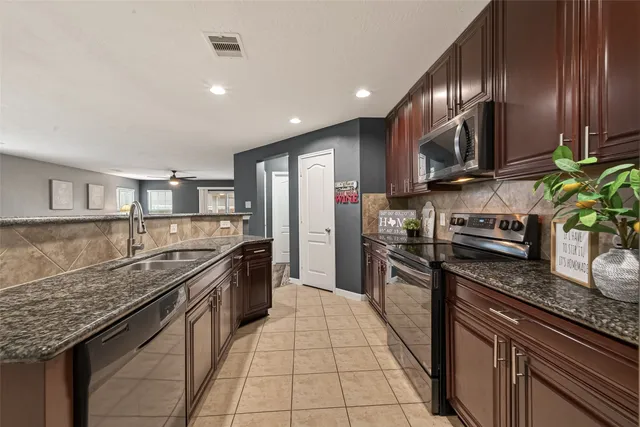a large kitchen with stainless steel appliances granite countertop a stove sink and cabinets