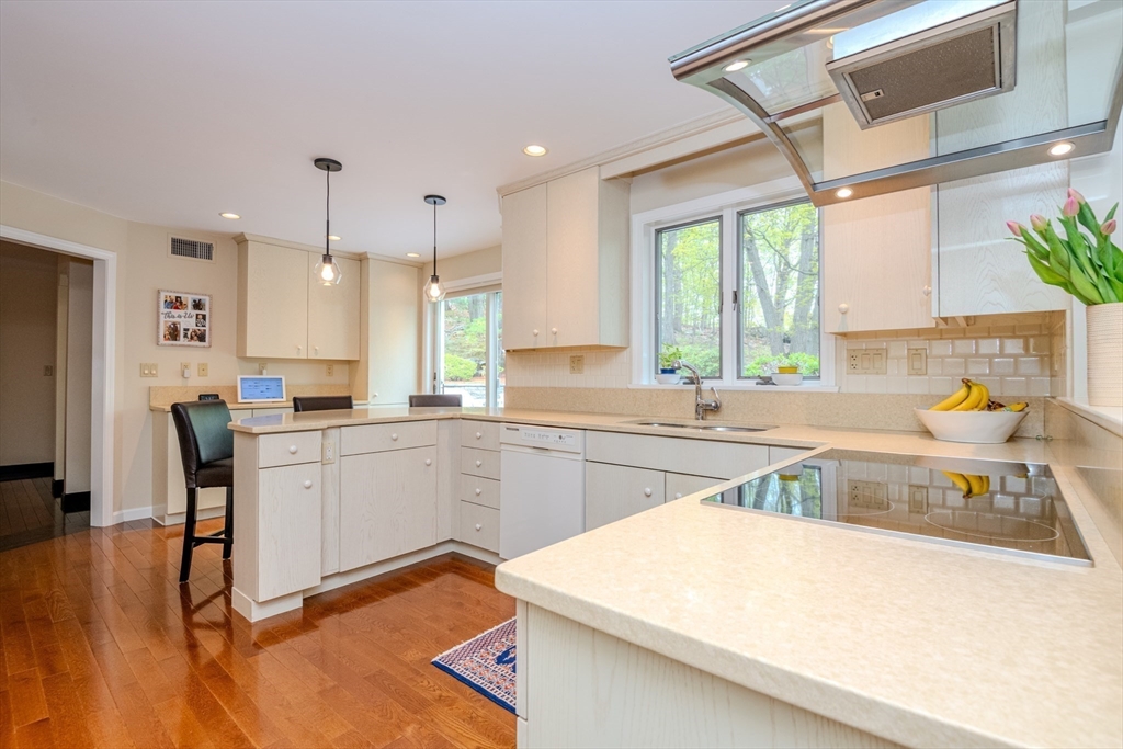 25 Ellen Road Stoneham, MA 02180 - Photo 15 of 41 a kitchen with a sink a stove a refrigerator and a dining table with wooden floor