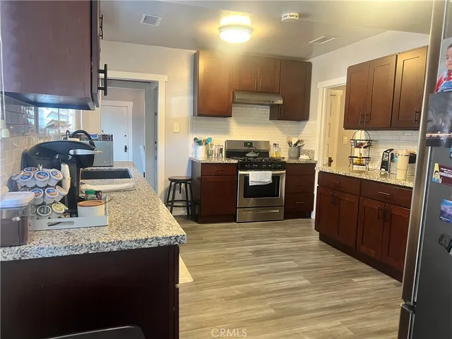 a kitchen with stainless steel appliances granite countertop a sink stove and refrigerator