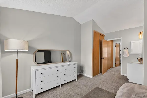 a bedroom with a bed and a lamp on dresser