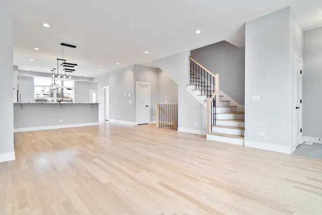 an empty room with wooden floor and kitchen view