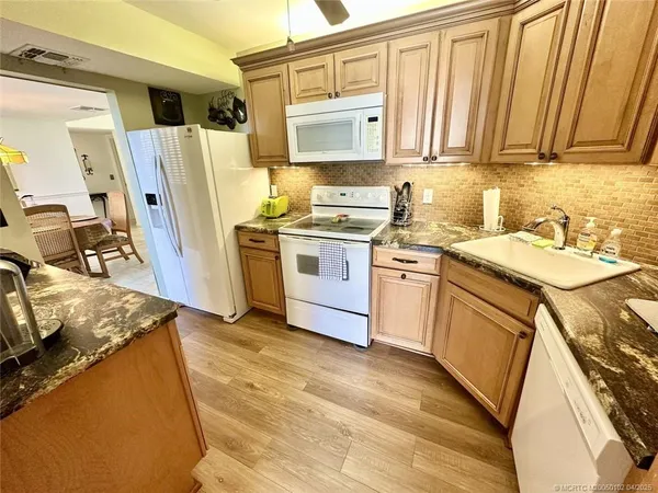 a kitchen with stainless steel appliances granite countertop a stove a sink dishwasher a refrigerator and cabinets with wooden floor