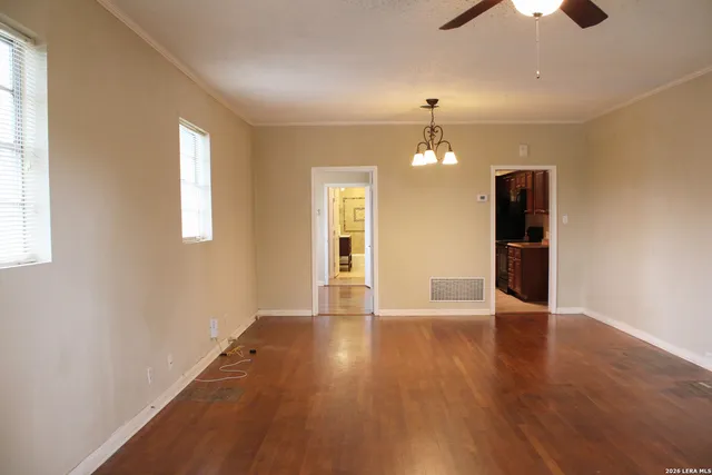 an empty room with chandelier fan and windows