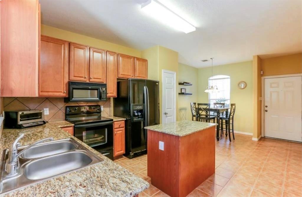 a kitchen with stainless steel appliances granite countertop sink stove refrigerator and cabinets