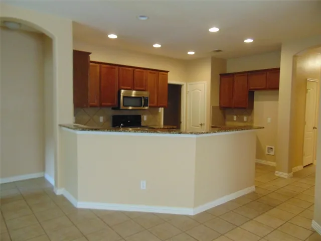 a kitchen with kitchen island granite countertop a refrigerator and a stove top oven
