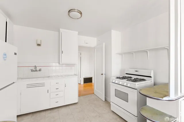 a kitchen with white cabinets and appliances