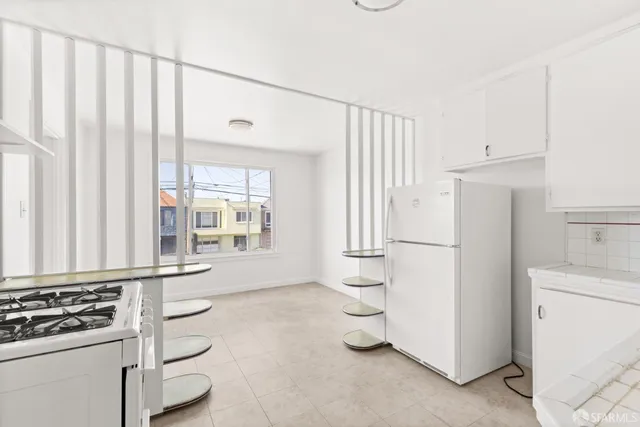 a kitchen with a refrigerator a stove and white cabinets
