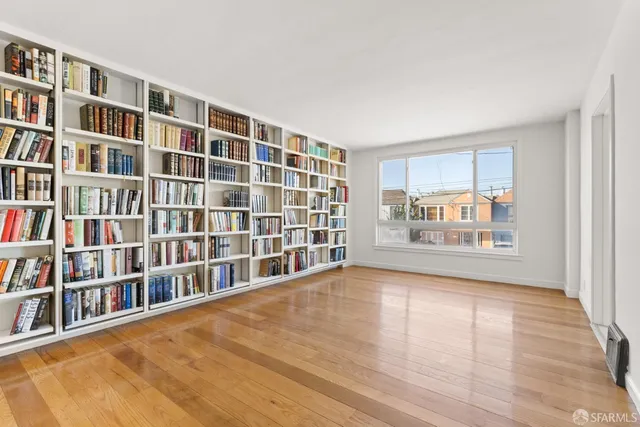 a view of an empty room with window and wooden floor