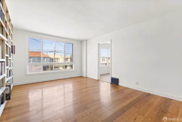 a view of an empty room with wooden floor and a window