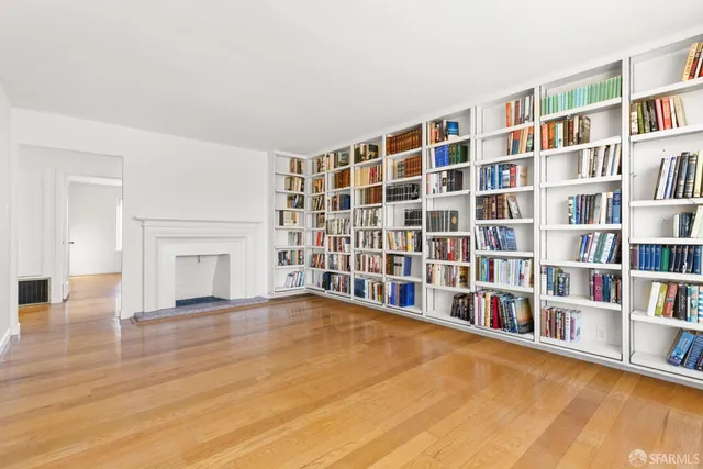 a view of an empty room with window and wooden floor