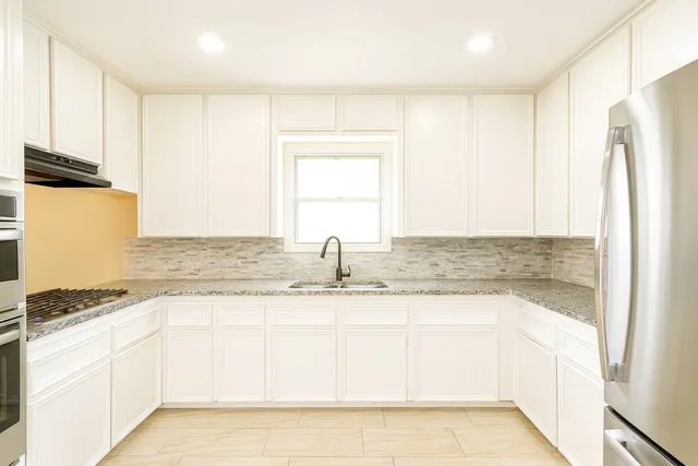 a kitchen with granite countertop a sink and a refrigerator