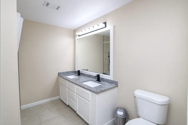 a bathroom with a granite countertop sink a toilet and mirror