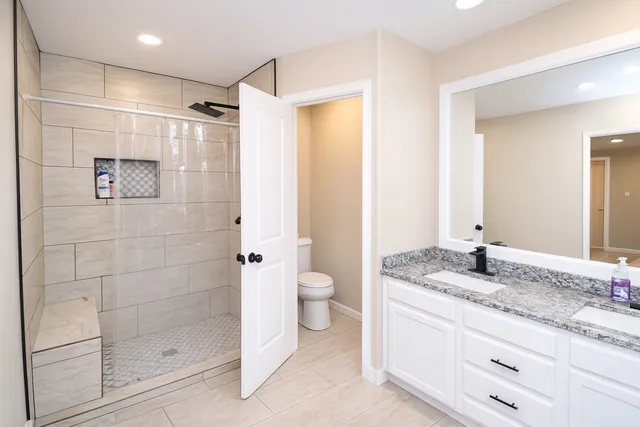 a bathroom with a granite countertop sink a toilet and shower