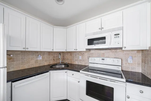 a kitchen with white cabinets and white appliances