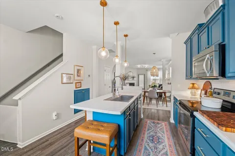 a large kitchen with kitchen island a stove a sink a dining table and chairs with wooden floor